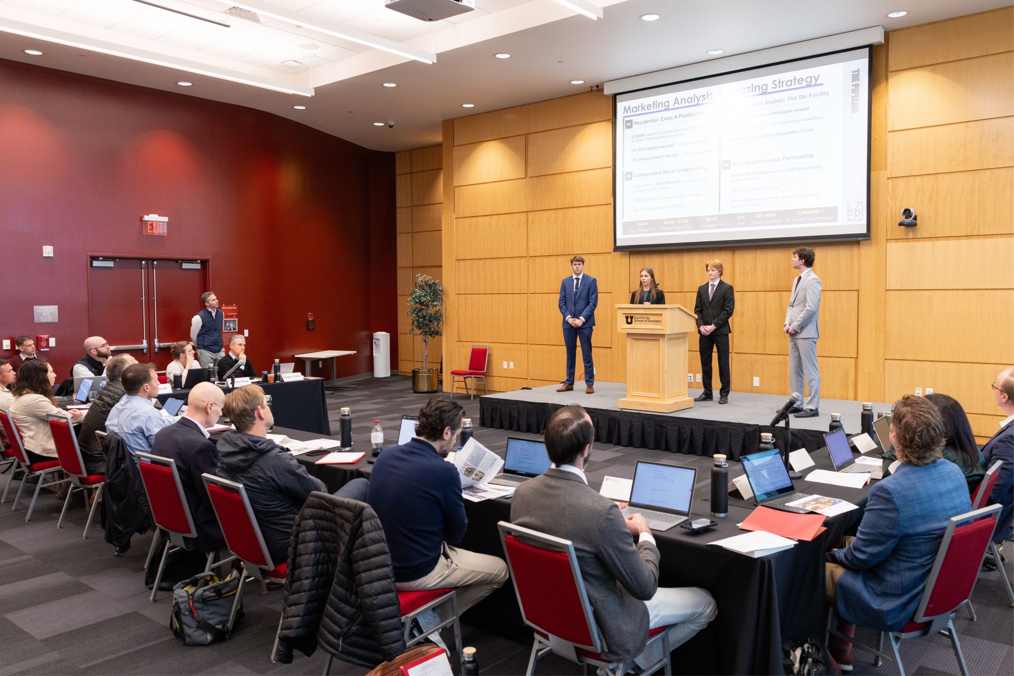 The Utah Real Estate Challenge team on stage at the David Eccles School of Business, presenting marketing analysis and leasing strategy to judges.